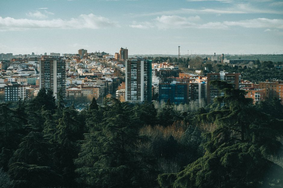 Vista aérea de una ciudad con edificios de gran altura y árboles frondosos en primer plano.