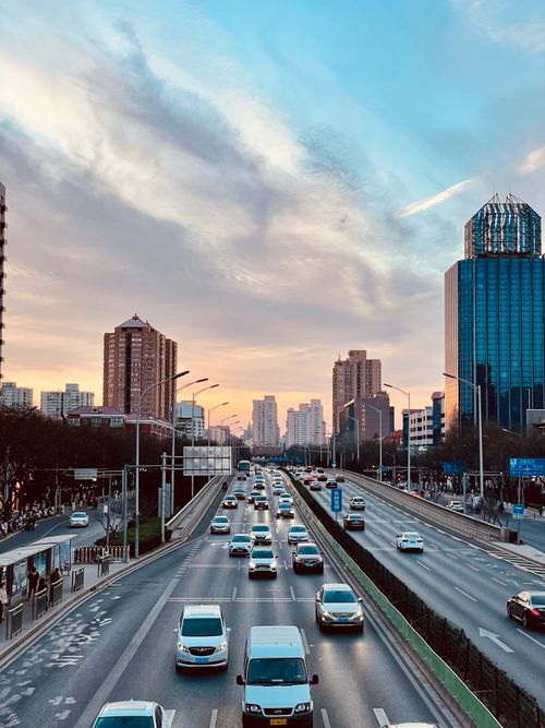 Free Urban evening traffic on a busy city highway amidst skyscrapers and a colorful sky. Stock Photo
