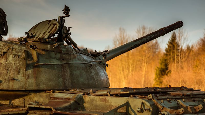 A rusted tank set against a forest background in Bosnia, highlighting historic military remnants.