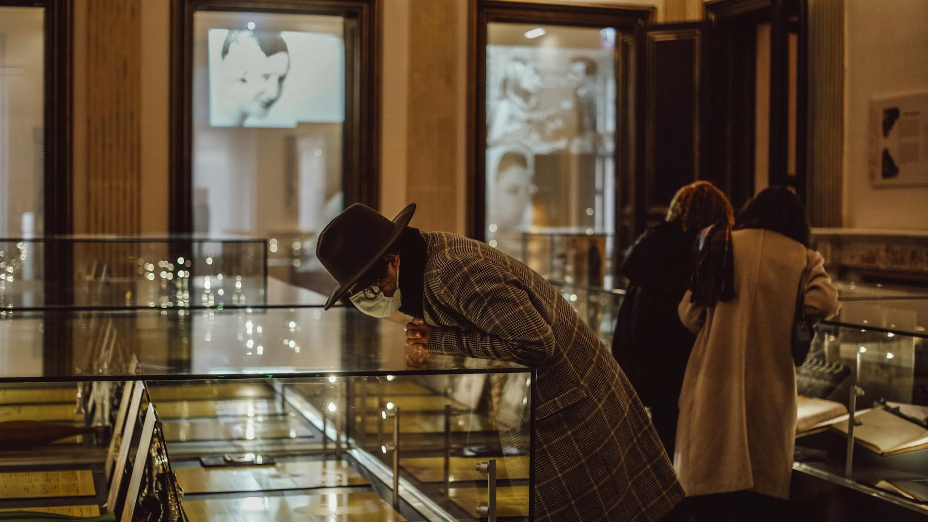 People in a museum viewing exhibits in glass cases, wearing winter clothing.