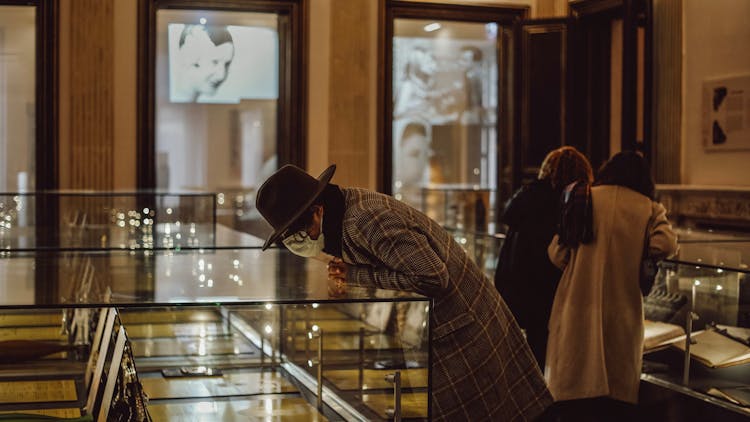 People Leaning Over Glass Cases Looking At Exhibit In Display