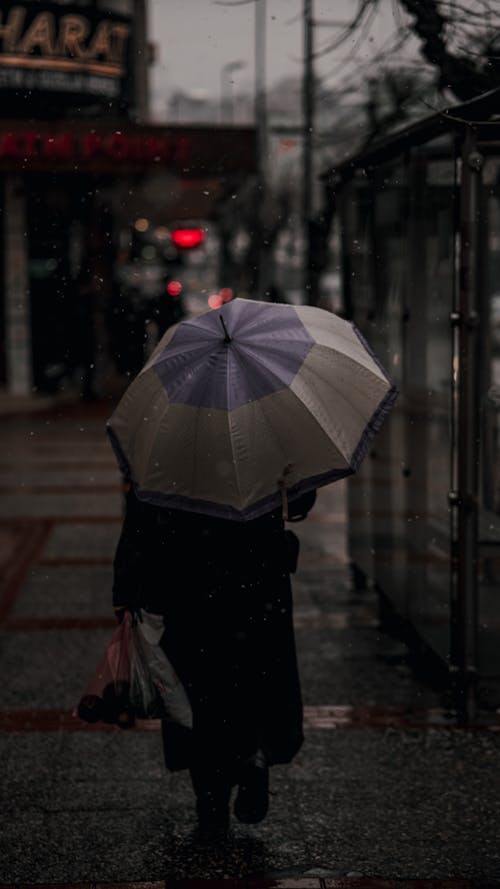 Free Person in Black Coat Holding Umbrella Walking on Sidewalk  Stock Photo