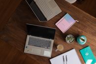 Macbook Pro Beside White Ceramic Mug on Brown Wooden Table