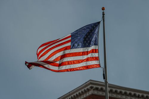 Free Close-up of a waving American flag on a pole against a cloudy sky in Denver, Colorado. Stock Photo