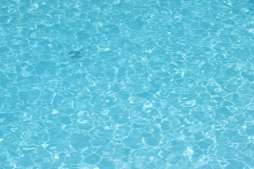 Close-up of clear blue water ripples in a swimming pool, creating a calming texture.