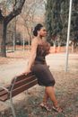 Woman in Brown Dress Sitting on Brown Wooden Bench