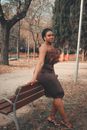 Woman in Black Dress Sitting on Brown Wooden Bench