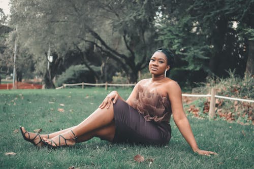 Woman in Brown Dress Sitting on Green Grass Field