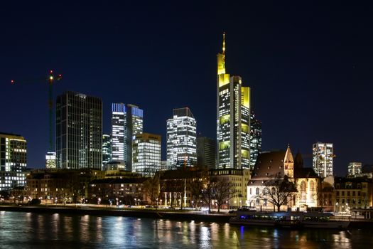 Stunning nighttime view of Frankfurt's illuminated skyline along the waterfront, showcasing modern architecture.