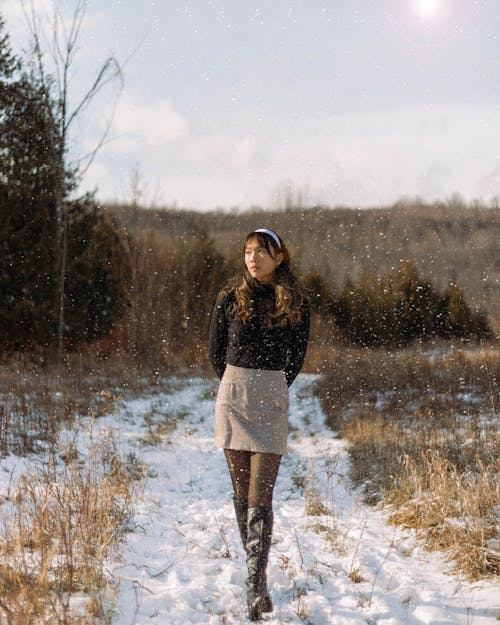 Woman in Black Sweater Walking Through Snow