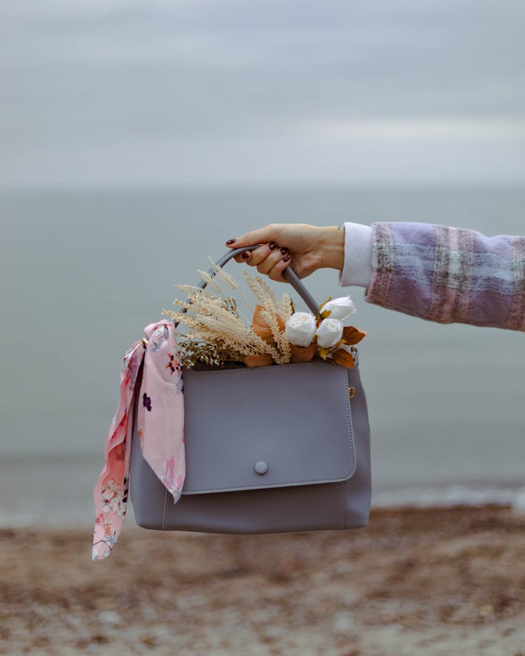 Hand Holding Handbag With Bouquet Inside