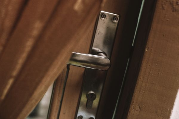A metal door handle slightly ajar against a wooden background.