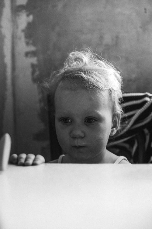 Free Monochrome image of a child looking thoughtful while sitting indoors. Stock Photo