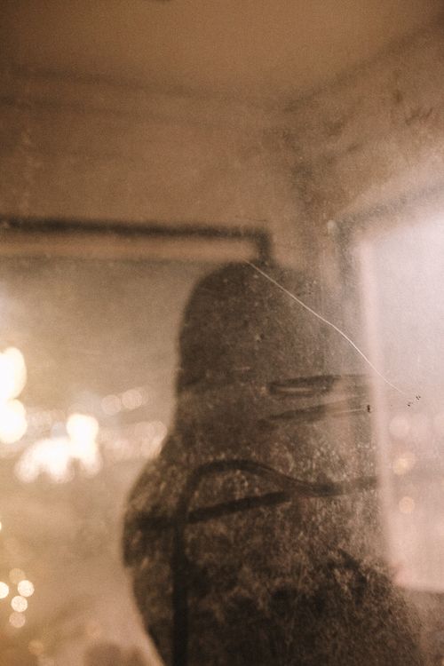 Free A mysterious silhouette appears behind a dusty window in a public transit setting, adding intrigue. Stock Photo