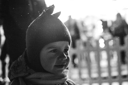 A Grayscale Photo of a Child Wearing Knitted Cap
