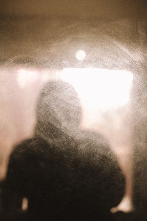 Free Artistic silhouette against bright light through a smudged glass window, creating an abstract effect. Stock Photo