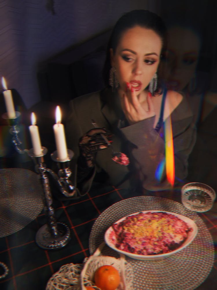 Woman Sitting In Front Of Candlelit Dinner Table