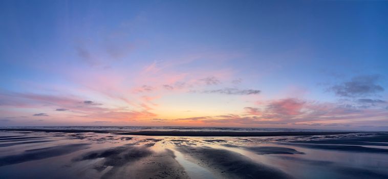 A stunning sunset with colorful skies over a calm ocean beach, creating a serene and picturesque view.