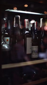 A vertical shot of multiple wine bottles stored on a bar shelf, ideal for a cozy setting.