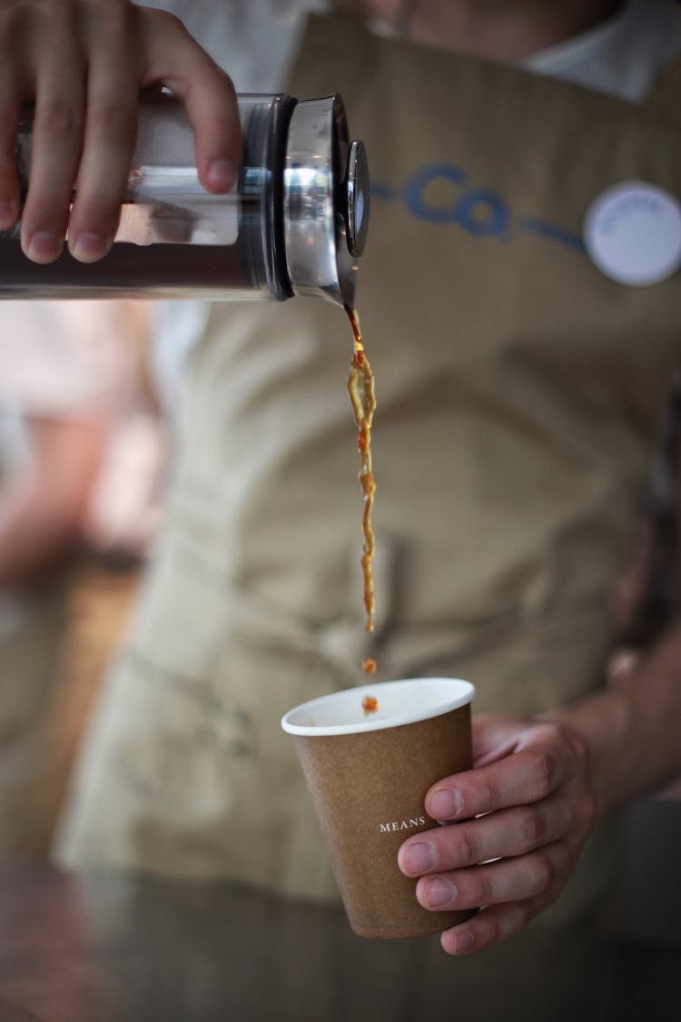 Barista Pouring Coffee Into A Paper Cup 