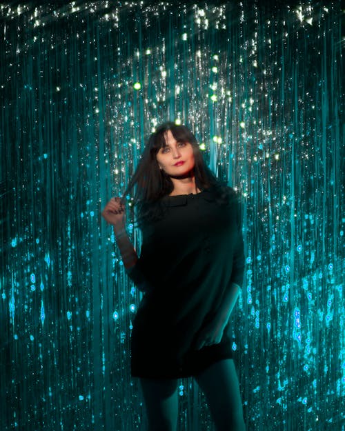 Brunette Woman standing against Turquoise Glittering Curtain