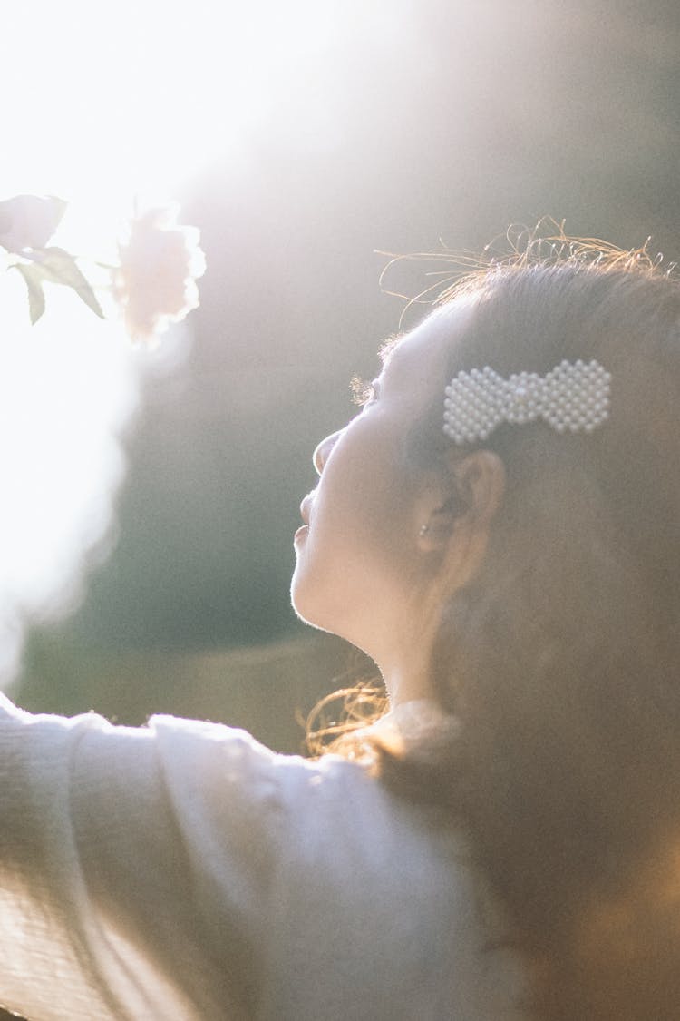 A Woman With A Clip Looking At A Flower