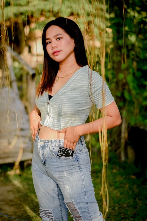 A Woman in Denim Pants Standing under the Tree