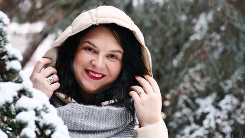 Free Portrait of a woman in winter clothing smiling in a snowy setting. Stock Photo