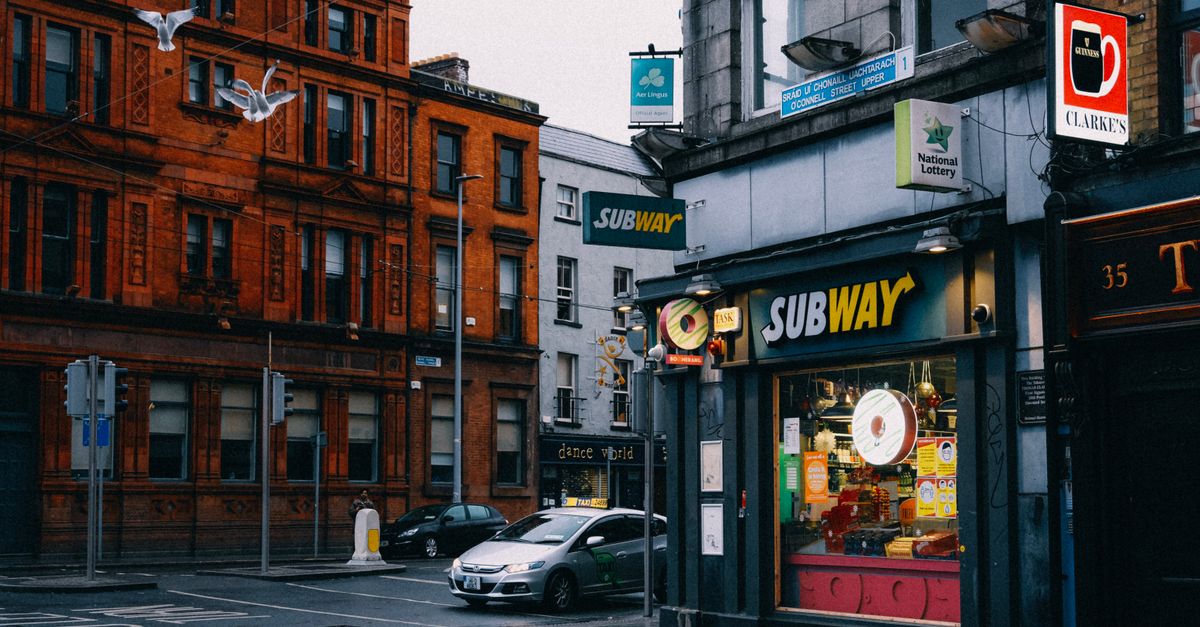 Busy urban street with Subway shop and historic architecture.
