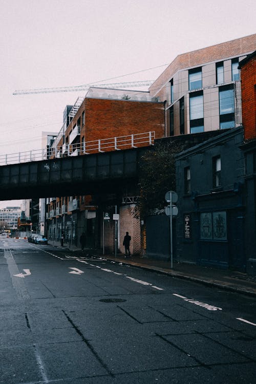 A Person Walking on the Street Under the Bridge