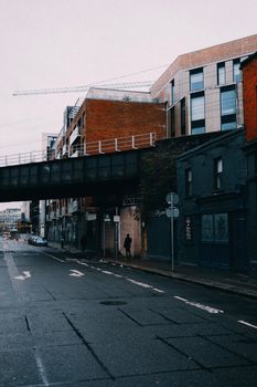 City street scene featuring a bridge, modern and old buildings, and urban atmosphere.