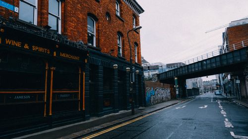 Free A moody city street scene featuring a historic brick building beside a metal overpass. Stock Photo