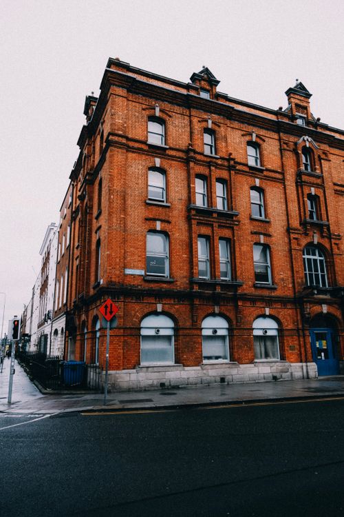 Free A striking red brick building stands on a deserted city street corner, showcasing urban architecture. Stock Photo