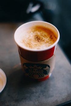 Artistic shot of a hot coffee in a red Starbucks cup with frothy top.