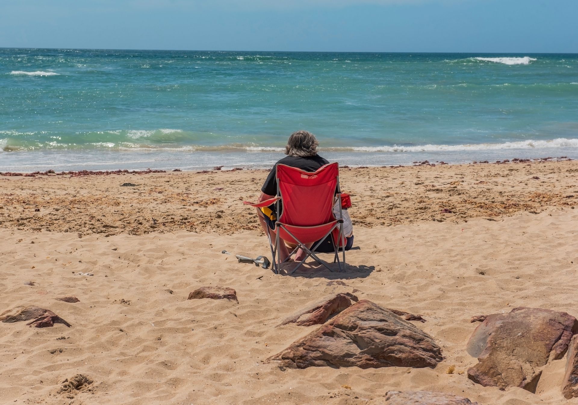 An adult sitting and relaxing by the ocean in Jeffreys Bay, capturing summer tranquility.