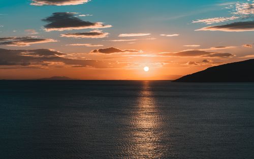 Free Calm ocean at sunset with golden sky and beautiful cloud formations, offering a tranquil seascape view. Stock Photo
