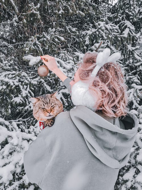 Woman in Gray Hoodie Holding a Cat While Snowing 
