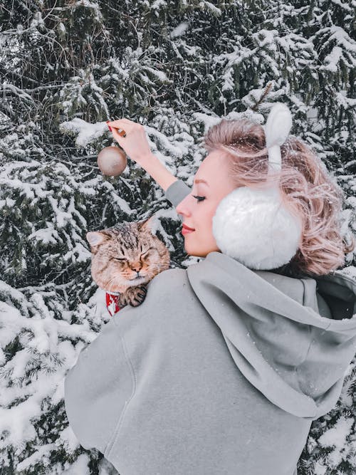 Woman in Gray Jacket Holding Brown Tabby Cat