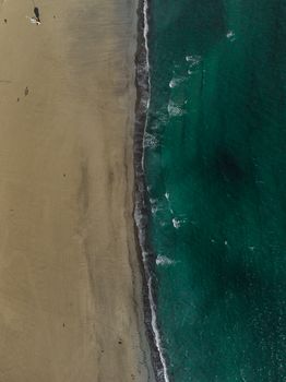 Stunning aerial shot of a sandy beach meeting turquoise ocean waves near Lübeck, Germany.