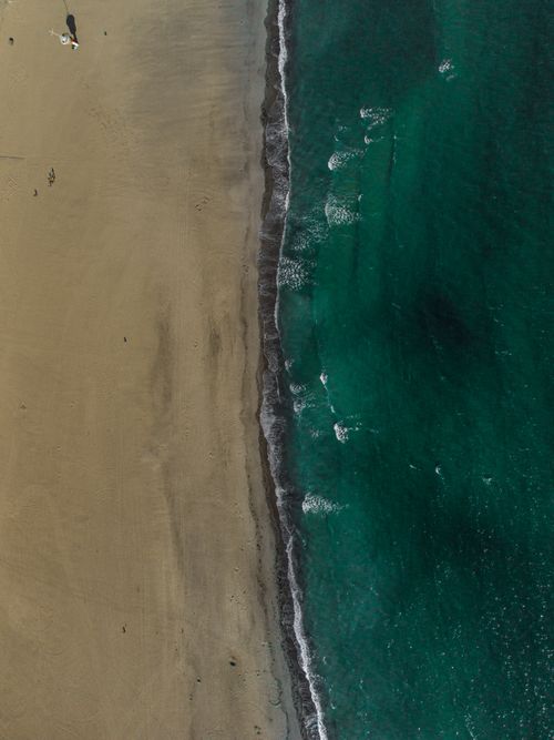 Free Stunning aerial shot of a sandy beach meeting turquoise ocean waves near Lübeck, Germany. Stock Photo