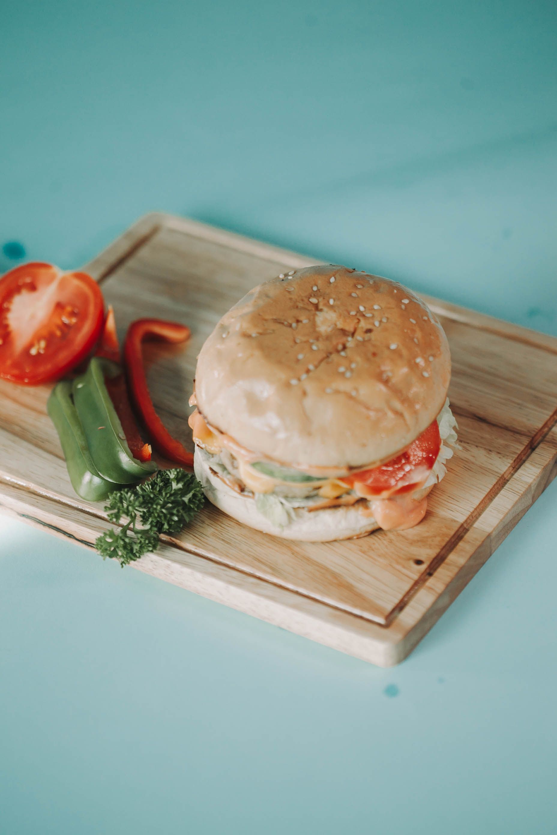 Delicious gourmet burger with fresh ingredients on a wooden tray, perfect for food photography enthusiasts.