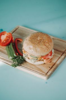 Delicious gourmet burger with fresh ingredients on a wooden tray, perfect for food photography enthusiasts.