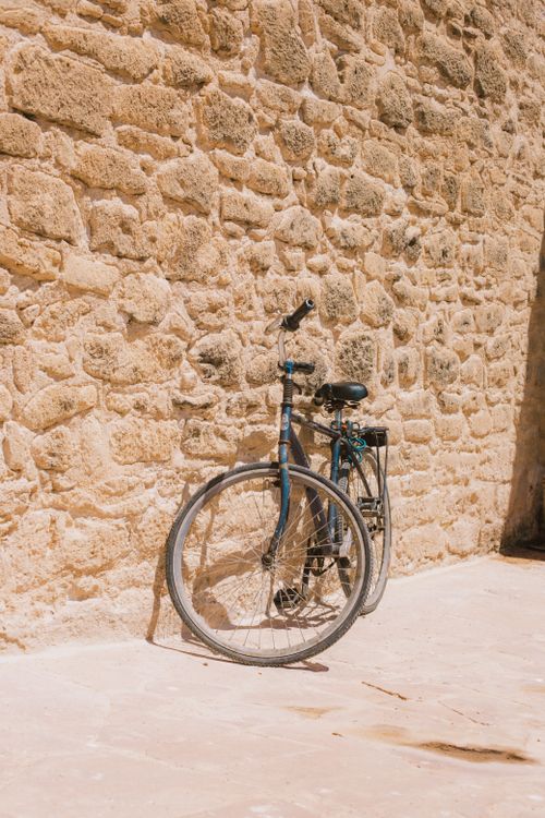 Free A vintage bicycle leaned against a rustic stone wall, capturing a nostalgic and timeless atmosphere. Stock Photo