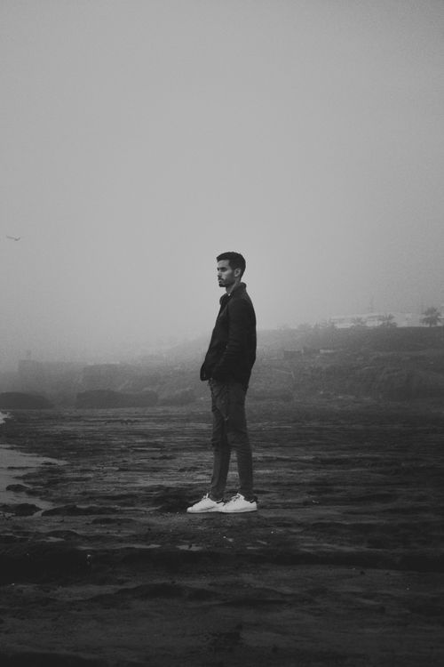 Free A solitary man stands on a foggy beach in Rabat, Morocco, with a moody atmosphere. Stock Photo