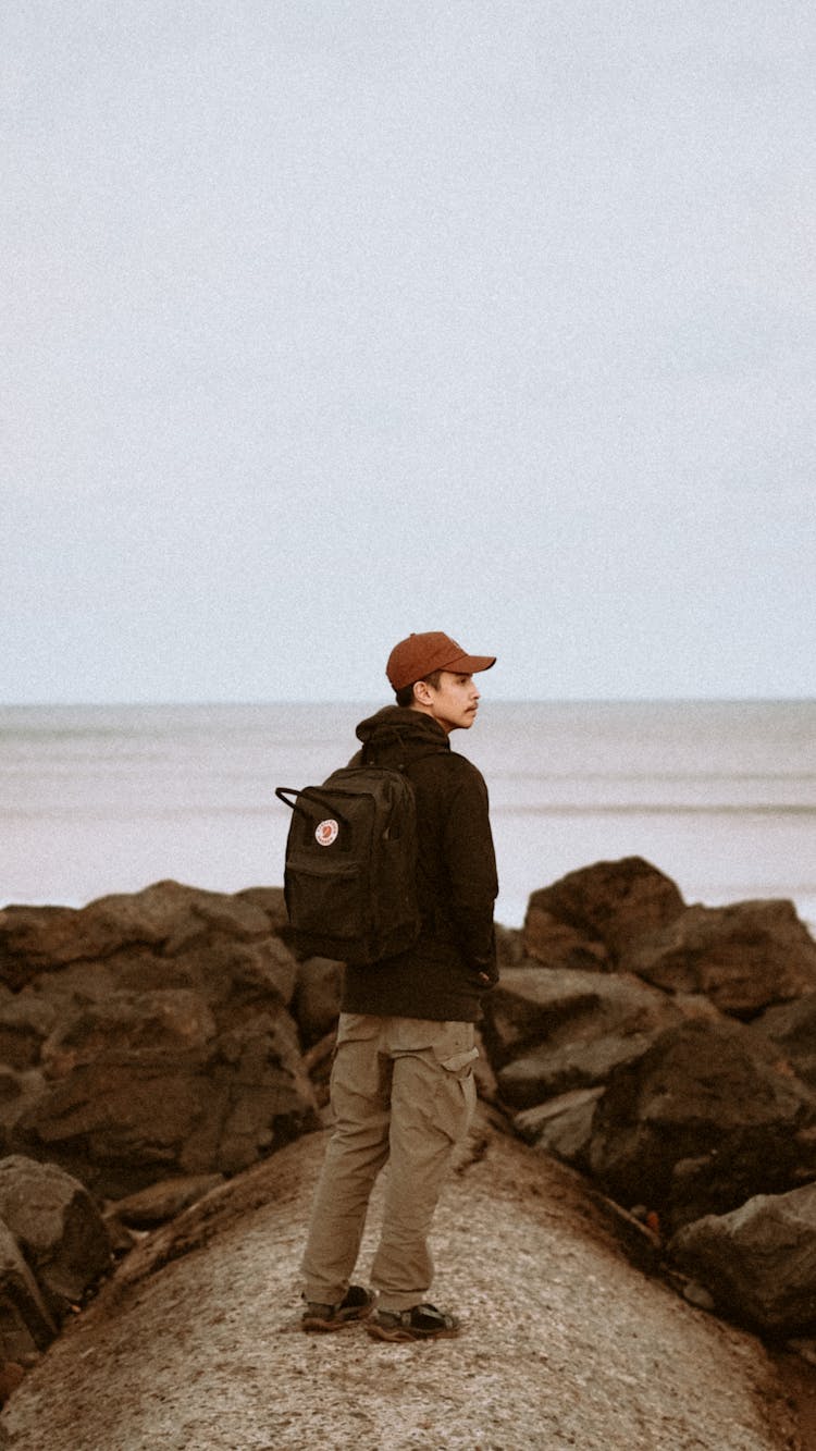 Young Man With A Backpack On A Seashore 