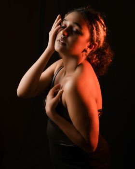 Artistic studio portrait of a woman in dim lighting, showcasing elegance and emotion.