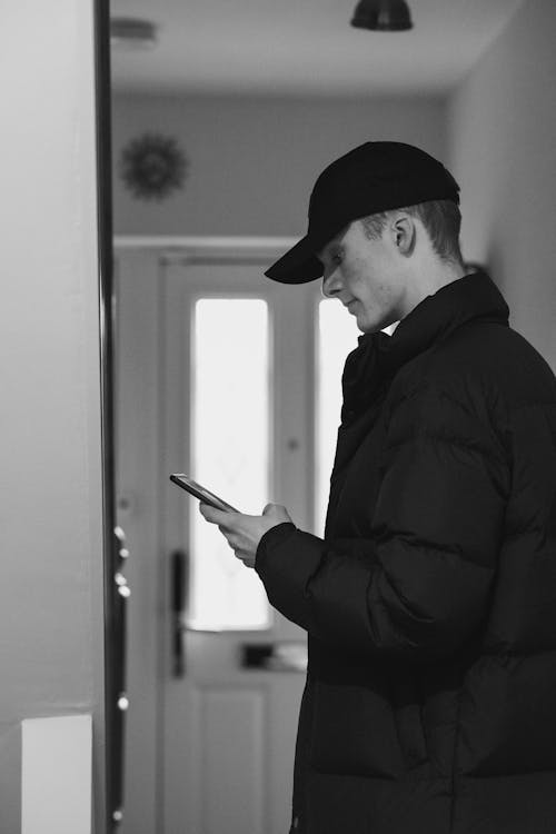 Man in Black Jacket and Black Cap Holding Smartphone