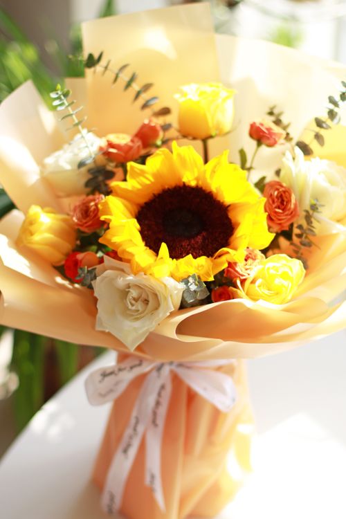 Free Elegant bouquet featuring a vibrant sunflower and delicate roses in soft natural light. Stock Photo