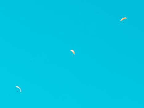 Two paragliders enjoying a clear sky adventure, symbolizing freedom and thrill.