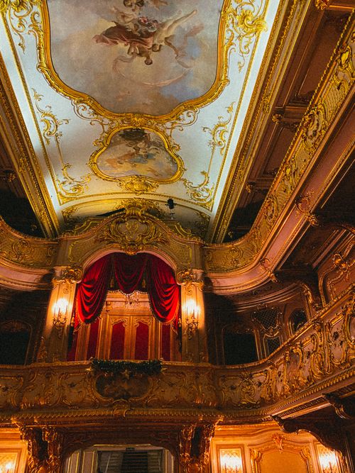Free Luxurious opera house interior with ornate gold decorations and classic red velvet curtains. Stock Photo